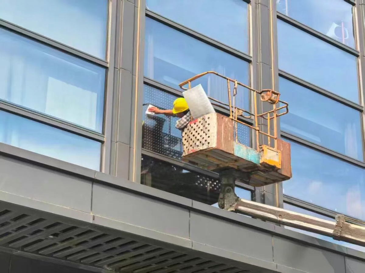 工人在大厦玻璃幕墙张贴贴纸